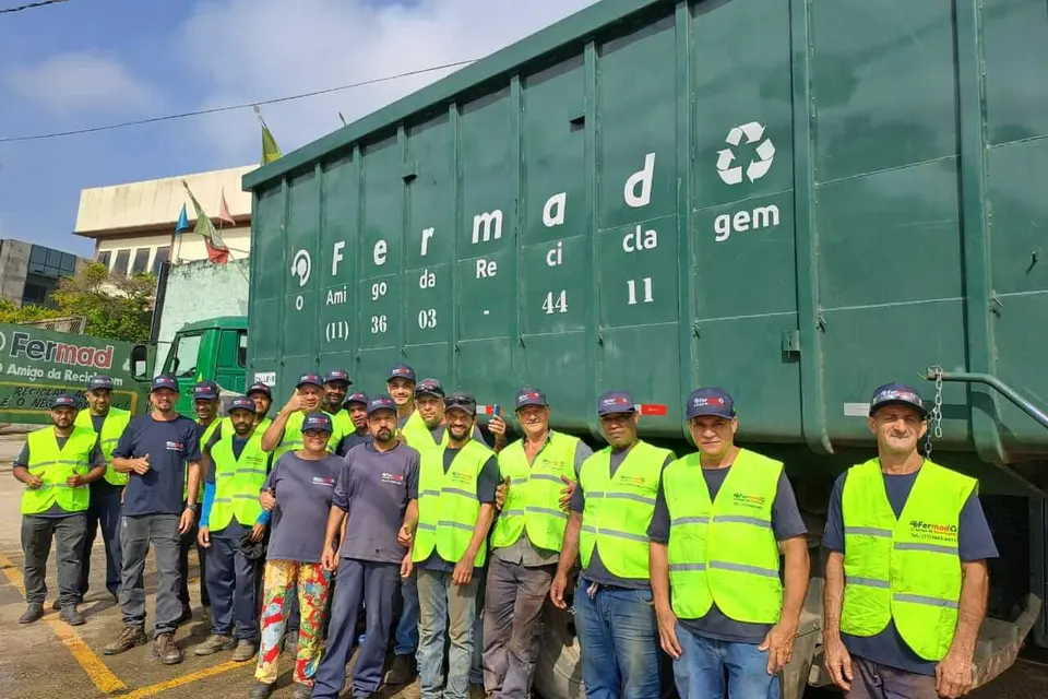Equipe da Fermad reunida em frente à caçamba verde da empresa